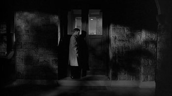 Movie still from “David and Lisa” (1962), directed by Frank Perry – A man standing in front of an open front door; Wide shot, Low angle