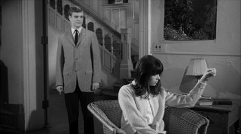Movie still from “David and Lisa” (1962), directed by Frank Perry – A man and a woman are standing in front of a staircase; Medium shot, Over the shoulder angle