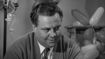 Movie still from “David and Lisa” (1962), directed by Frank Perry – An old black and white photo of a man in a sweater and tie; Close Up shot, Over the shoulder angle