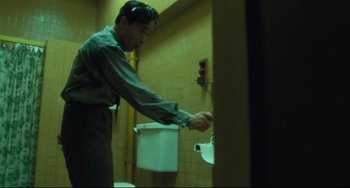 Movie still from “Days of Being Wild” (1990), directed by Kar-Wai Wong – A man in a bathroom putting something in a urinal; Medium shot, Low angle