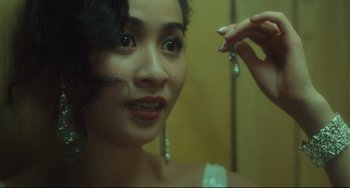 Movie still from “Days of Being Wild” (1990), directed by Kar-Wai Wong – A woman is looking into a mirror and holding a pair of dangling earrings; Close Up shot, Over the shoulder angle