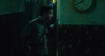 Movie still from “Days of Being Wild” (1990), directed by Kar-Wai Wong – A man standing next to a wall in a dark room; Medium shot, Over the shoulder angle