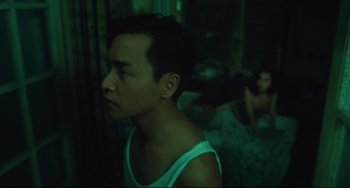 Movie still from “Days of Being Wild” (1990), directed by Kar-Wai Wong – A man in a white tank top is in a dark room; Medium shot, Over the shoulder angle