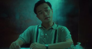 Movie still from “Days of Being Wild” (1990), directed by Kar-Wai Wong – A young man sitting at a table with his arms crossed; Medium shot, Low angle