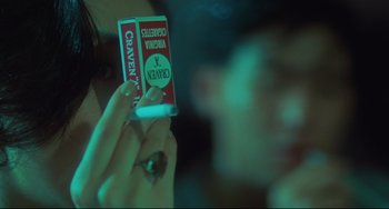 Movie still from “Days of Being Wild” (1990), directed by Kar-Wai Wong – A person holding a pack of cigarettes in their hand; Extreme Close Up shot, Over the shoulder angle