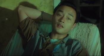 Movie still from “Days of Being Wild” (1990), directed by Kar-Wai Wong – A man sitting on top of a couch with his arms behind his head; Medium shot, Low angle