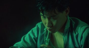 Movie still from “Days of Being Wild” (1990), directed by Kar-Wai Wong – A man holding a glass pipe while sitting down; Close Up shot, High angle