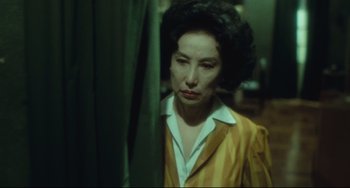 Movie still from “Days of Being Wild” (1990), directed by Kar-Wai Wong – A woman in a yellow and white striped jacket looking out a window; Close Up shot, High angle