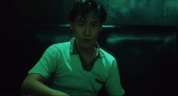 Movie still from “Days of Being Wild” (1990), directed by Kar-Wai Wong – A young man sitting in a chair in a dark room; Close Up shot, Low angle