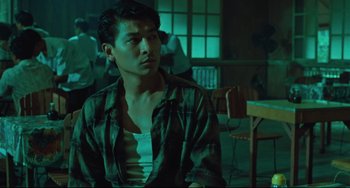 Movie still from “Days of Being Wild” (1990), directed by Kar-Wai Wong – A man sitting in front of a group of people in a room; Medium shot, Low angle