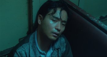 Movie still from “Days of Being Wild” (1990), directed by Kar-Wai Wong – A young man with wet hair is sitting in a corner; Close Up shot, High angle