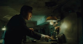 Movie still from “Days of Being Wild” (1990), directed by Kar-Wai Wong – A man smoking a cigarette in front of a computer monitor; Medium shot, Low angle