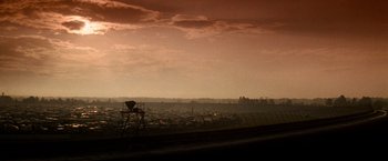 Movie still from “Days of Thunder” (1990), directed by Tony Scott – A view of a city from a distance with a tower in the foreground; Extreme Wide shot, Low angle