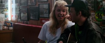 Movie still from “Days of Thunder” (1990), directed by Tony Scott – A young woman smiles as she talks to a young man; Close Up shot, Over the shoulder angle