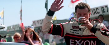Movie still from “Days of Thunder” (1990), directed by Tony Scott – A man in a racing suit waving at a crowd; Medium shot, Low angle