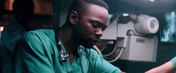Movie still from “Days of Thunder” (1990), directed by Tony Scott – A male doctor wearing a stethoscope is looking down; Close Up shot, Low angle