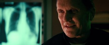 Movie still from “Days of Thunder” (1990), directed by Tony Scott – An old man with a goatee and a smirk on his face; Close Up shot, Low angle