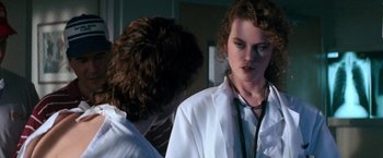 Movie still from “Days of Thunder” (1990), directed by Tony Scott – A woman in white lab coat with a stethoscope around her neck; Close Up shot, Over the shoulder angle