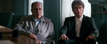 Movie still from “Days of Thunder” (1990), directed by Tony Scott – Two men sitting next to each other in a room; Medium shot, Over the shoulder angle