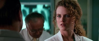 Movie still from “Days of Thunder” (1990), directed by Tony Scott – A person wearing a lab coat; Close Up shot, Over the shoulder angle