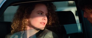 Movie still from “Days of Thunder” (1990), directed by Tony Scott – A woman with curly red hair sitting in the back of a car; Close Up shot, Low angle