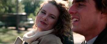 Movie still from “Days of Thunder” (1990), directed by Tony Scott – A person with curly hair smiling; Close Up shot, Over the shoulder angle