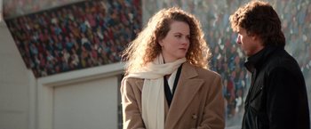 Movie still from “Days of Thunder” (1990), directed by Tony Scott – A person with curly hair wearing a coat; Medium shot, Over the shoulder angle
