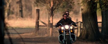 Movie still from “Days of Thunder” (1990), directed by Tony Scott – A man and woman riding a motorcycle down a road; Wide shot, Low angle