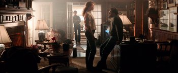 Movie still from “Days of Thunder” (1990), directed by Tony Scott – Two people standing in a living room talking to each other; Wide shot, Low angle