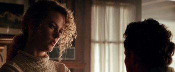 Movie still from “Days of Thunder” (1990), directed by Tony Scott – A woman with curly blonde hair standing next to a window; Close Up shot, Over the shoulder angle