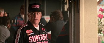 Movie still from “Days of Thunder” (1990), directed by Tony Scott – A man in a black and red racing suit; Medium shot, Over the shoulder angle