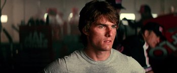 Movie still from “Days of Thunder” (1990), directed by Tony Scott – A person wearing a gray t - shirt; Close Up shot, Over the shoulder angle