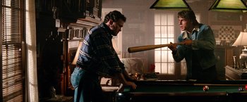 Movie still from “Days of Thunder” (1990), directed by Tony Scott – A man holding a baseball bat over a pool table; Medium shot, Over the shoulder angle