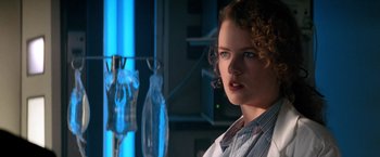 Movie still from “Days of Thunder” (1990), directed by Tony Scott – A woman with curly hair standing in front of a blue background; Close Up shot, Low angle