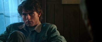 Movie still from “Days of Thunder” (1990), directed by Tony Scott – A man in a denim jacket sitting in front of a wooden wall; Close Up shot, Over the shoulder angle