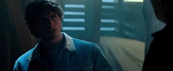Movie still from “Days of Thunder” (1990), directed by Tony Scott – A man wearing a jean jacket is sitting in a room; Close Up shot, Over the shoulder angle