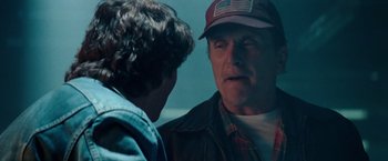 Movie still from “Days of Thunder” (1990), directed by Tony Scott – A man wearing a baseball cap talking to another man; Close Up shot, Over the shoulder angle