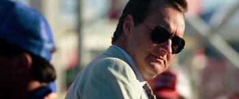 Movie still from “Days of Thunder” (1990), directed by Tony Scott – A person wearing a suit and sunglasses; Close Up shot, Low angle