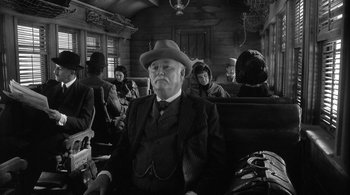 Movie still from “Dead Man” (1995), directed by Jim Jarmusch – An old man sitting in a train car with people sitting around him; Medium shot, Low angle