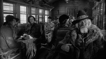 Movie still from “Dead Man” (1995), directed by Jim Jarmusch – A black and white photo of a group of people sitting on a train; Medium shot, Over the shoulder angle