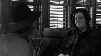 Movie still from “Dead Man” (1995), directed by Jim Jarmusch – Two people sitting on a couch in front of a window; Close Up shot, Over the shoulder angle