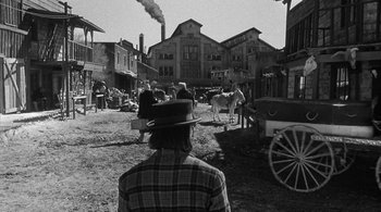 Movie still from “Dead Man” (1995), directed by Jim Jarmusch – An old photo of a man in a plaid shirt and a cowboy hat; Wide shot, Over the shoulder angle