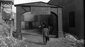 Movie still from “Dead Man” (1995), directed by Jim Jarmusch – A man standing in front of an old building; Wide shot, High angle