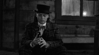 Movie still from “Dead Man” (1995), directed by Jim Jarmusch – A man in a top hat holding a cell phone; Medium shot, Low angle