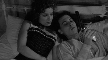 Movie still from “Dead Man” (1995), directed by Jim Jarmusch – A man and a woman laying next to each other holding a gun; Close Up shot, High angle