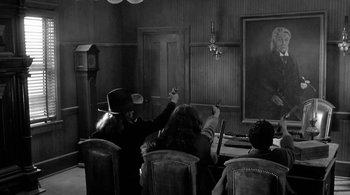 Movie still from “Dead Man” (1995), directed by Jim Jarmusch – A group of people sitting in front of a projector screen; Wide shot, Low angle