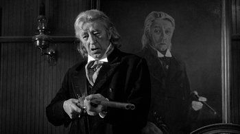 An old man holding a knife in front of a painting of himself