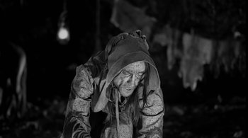 Movie still from “Dead Man” (1995), directed by Jim Jarmusch – An old woman wearing a hat and a jacket; Medium shot, High angle