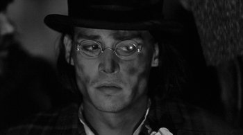 Movie still from “Dead Man” (1995), directed by Jim Jarmusch – A man wearing a hat and glasses; Close Up shot, Low angle