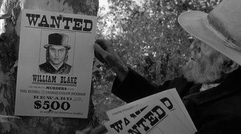 Movie still from “Dead Man” (1995), directed by Jim Jarmusch – A person holding a wanted poster next to a tree; Close Up shot, Low angle
